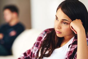 Young woman sad with partner in background